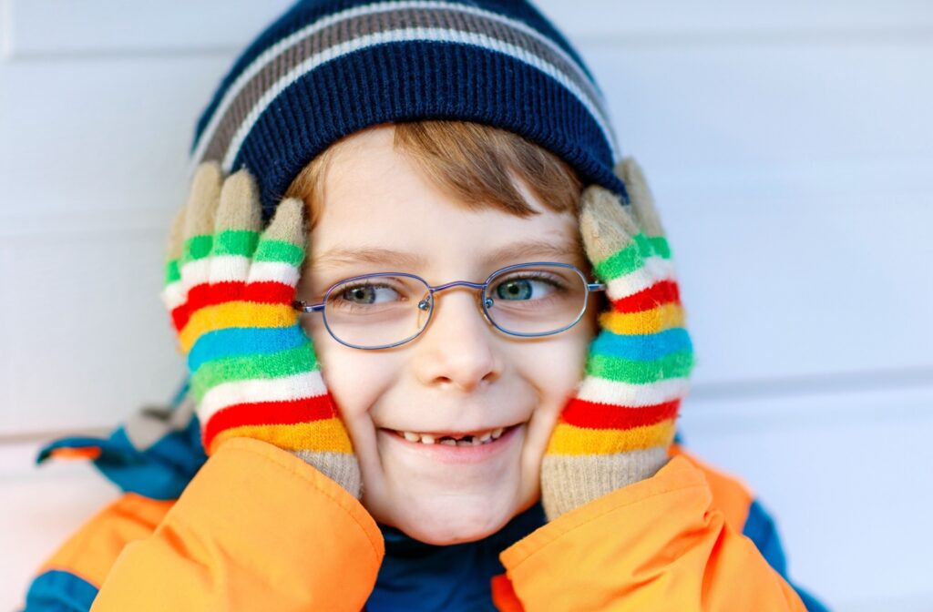 A smiling child wears glasses and colourful winter clothing showcasing clear vision and confidence