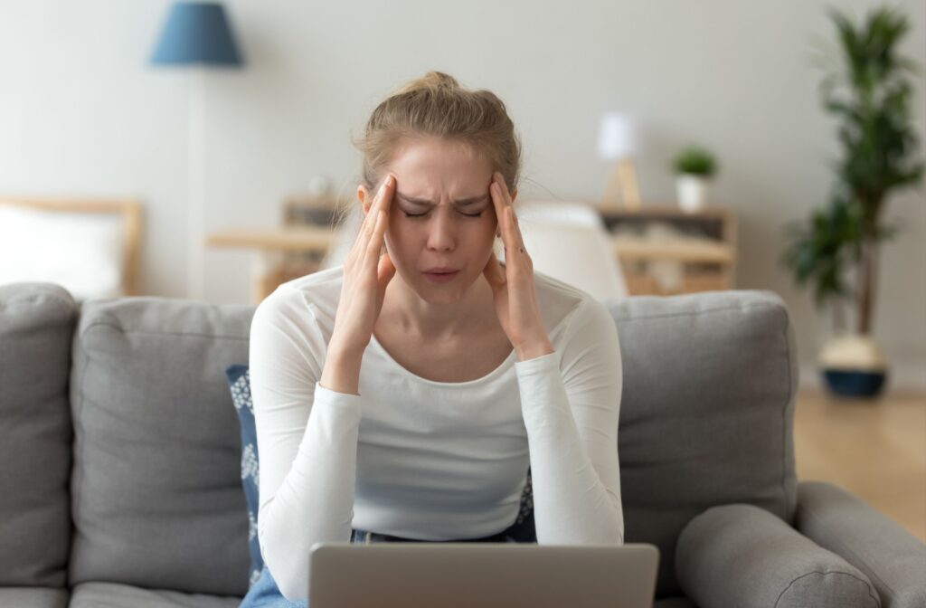 Person experiencing discomfort from digital eye strain while using a laptop.