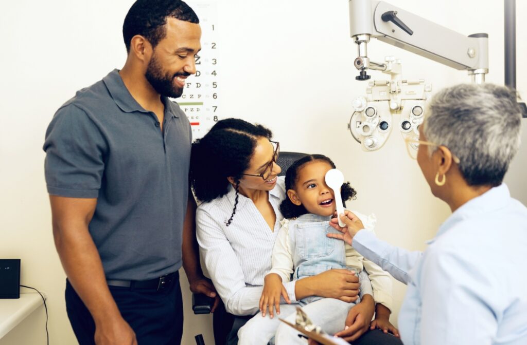 Family in Saskatoon smiling as a child sits on their mother’s lap during an eye exam.